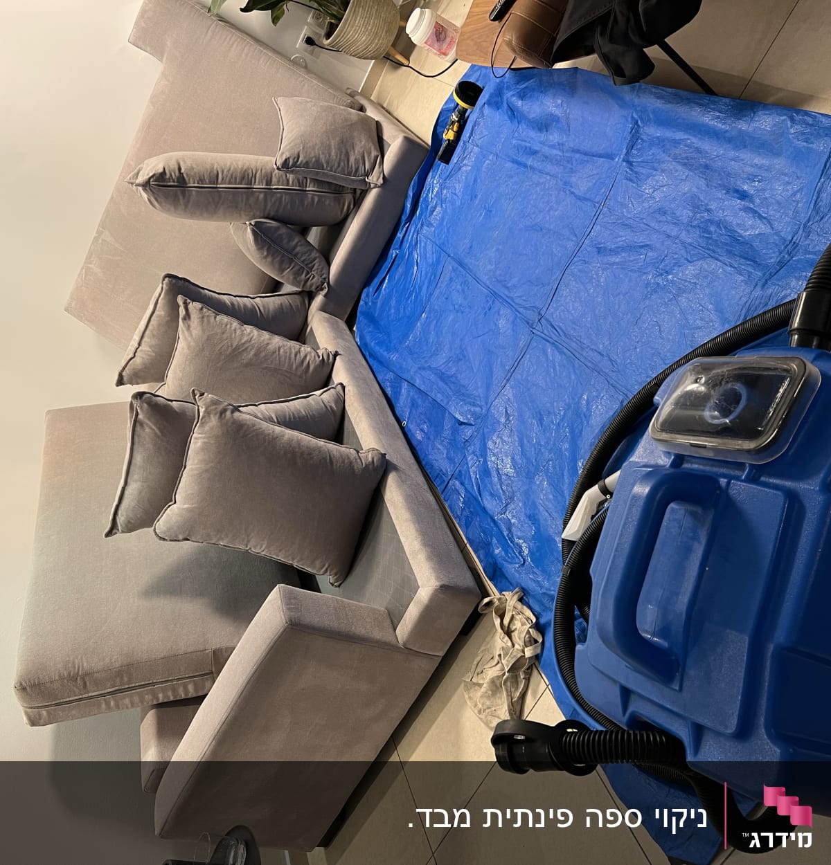 מכונת ניקוי כחולה ליד ספה וכיסוי כחול